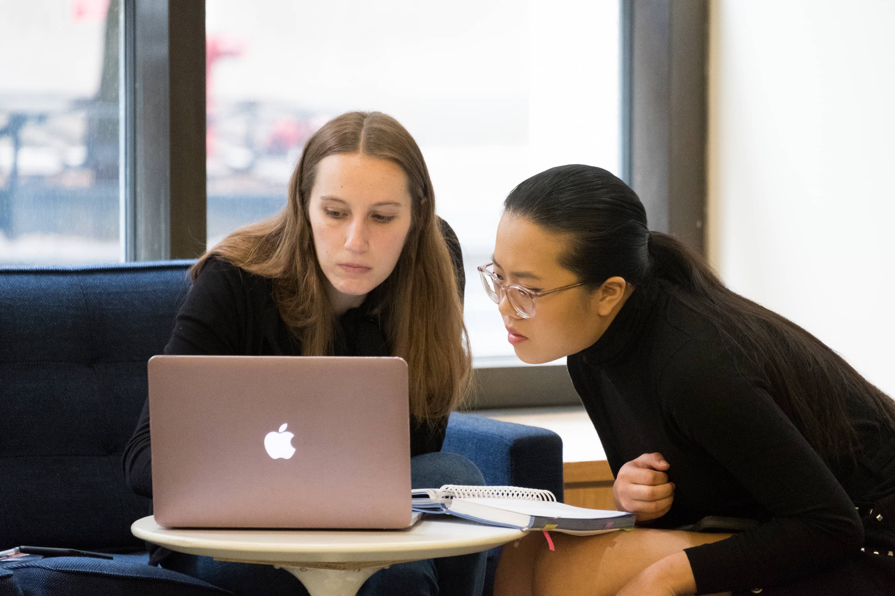 Two students play a piano in one of the common areas